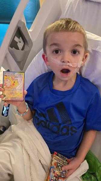 A boy in the hospital lighting up over a Pokemon card
